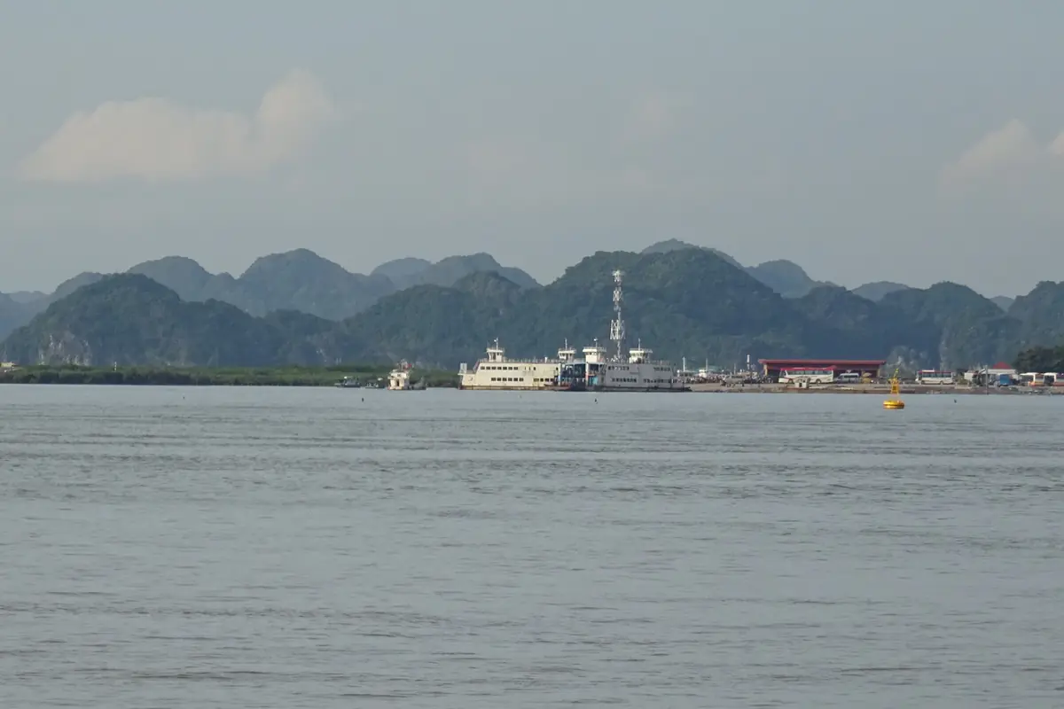 Cai Vieng ferry pier on Cat Ba Island seen from the water, limestone hills behind, August 2018