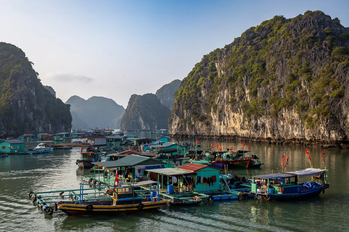 Floating houses and boats at Cai Beo fishing village below limestone cliffs, the gateway to Lan Ha Bay, March 2024