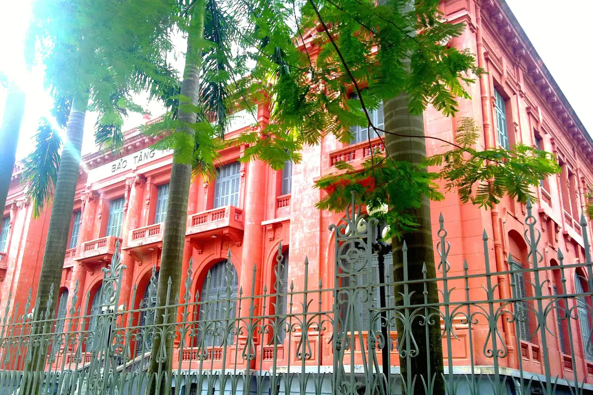 Tòa nhà Bảo tàng Hải Phòng màu đỏ gạch sau hàng rào sắt và tán cây